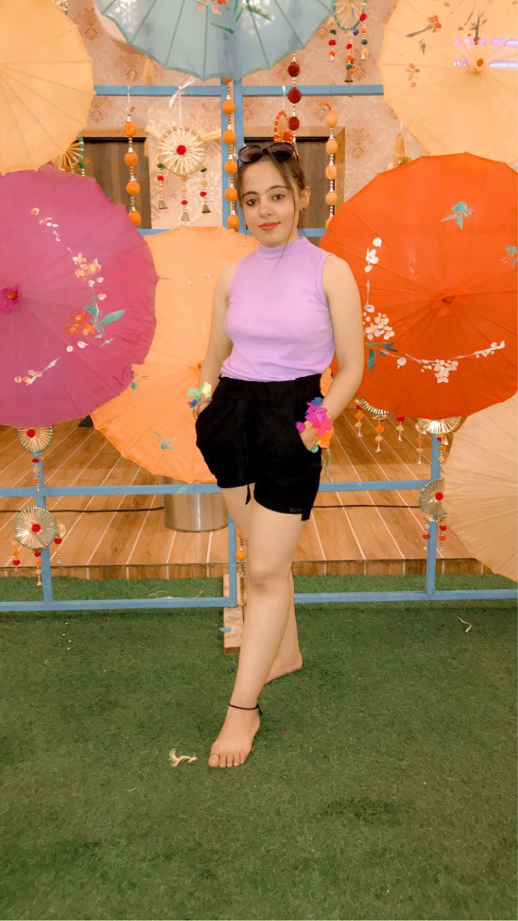 Nishu standing in front of colourful decorative umbrellas.